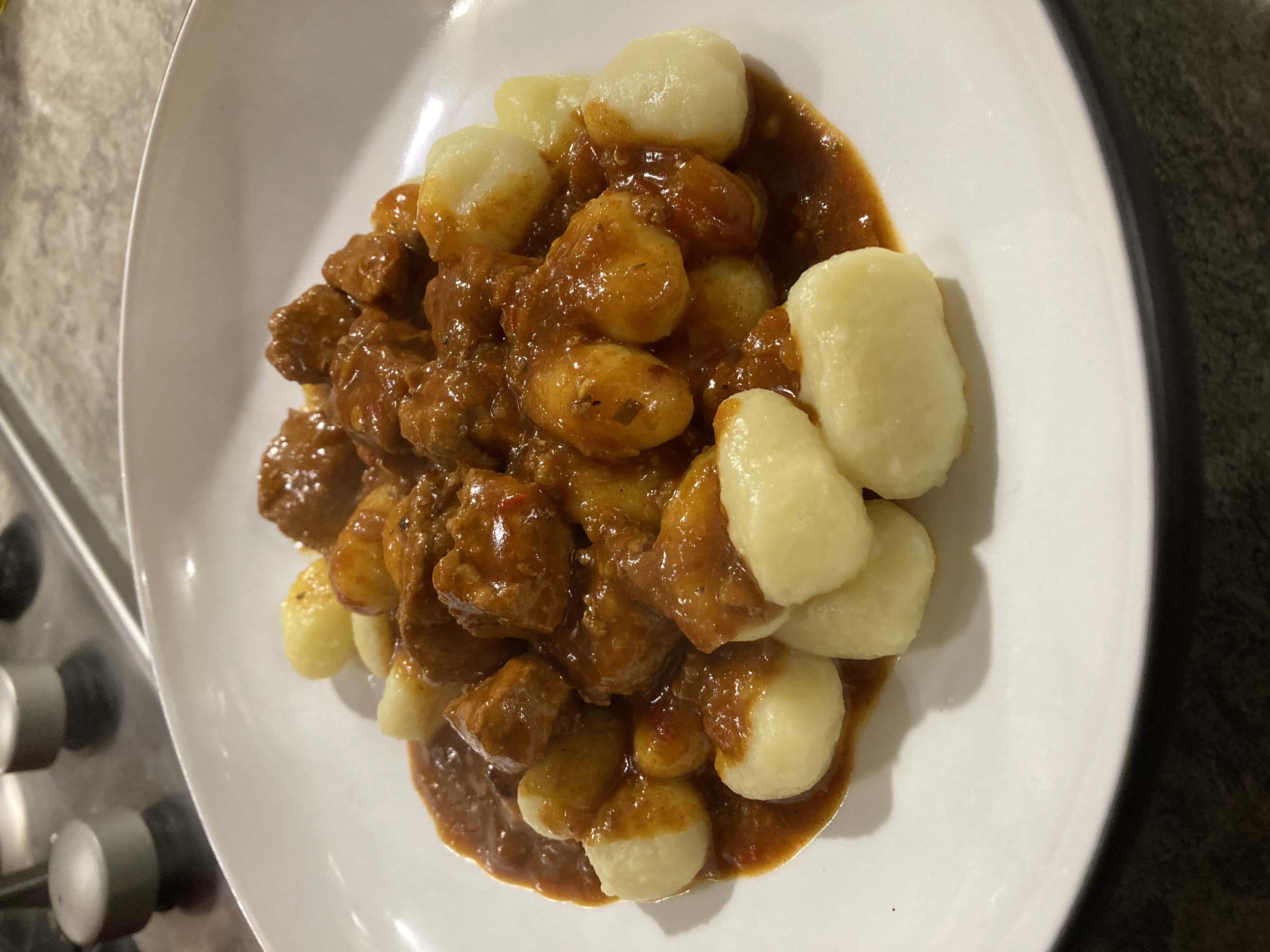 A plate with the finished goulash and some gnocchi